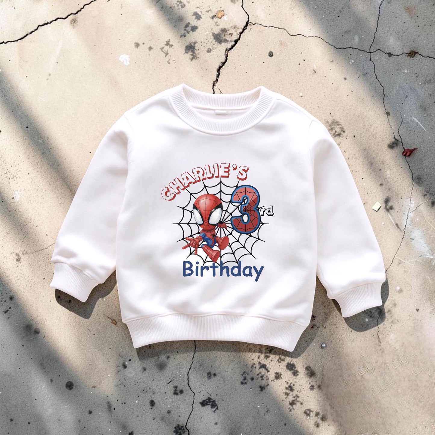 A white sweatshirt with a Spiderman design and the text "Charlie's Birthday" printed on it.