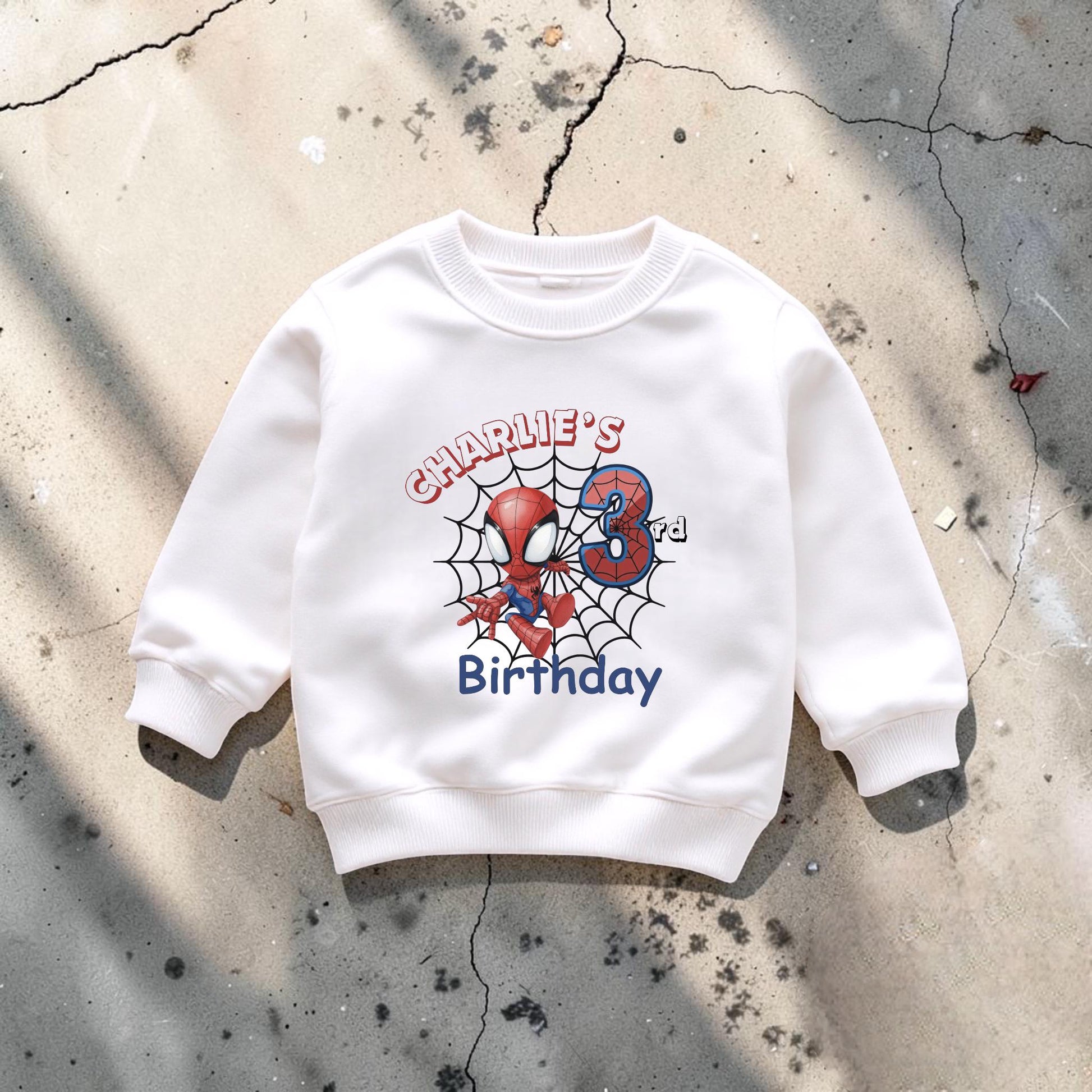 A white sweatshirt with a Spiderman design and the text "Charlie's Birthday" printed on it.