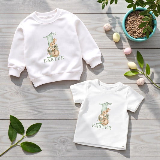 White baby sweatshirt and t-shirt featuring a printed “My First Easter” bunny design in soft sage tones.