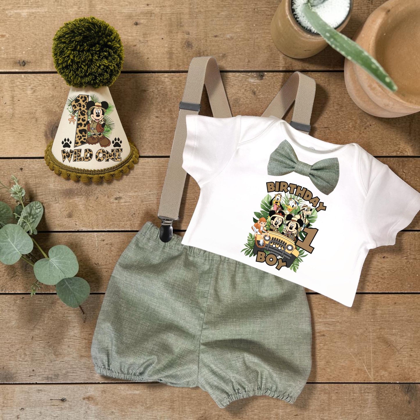 Personalised Wild One safari birthday outfit with sage green bloomers, suspenders, bow tie, printed bodysuit and handmade safari party hat for first birthday celebrations.