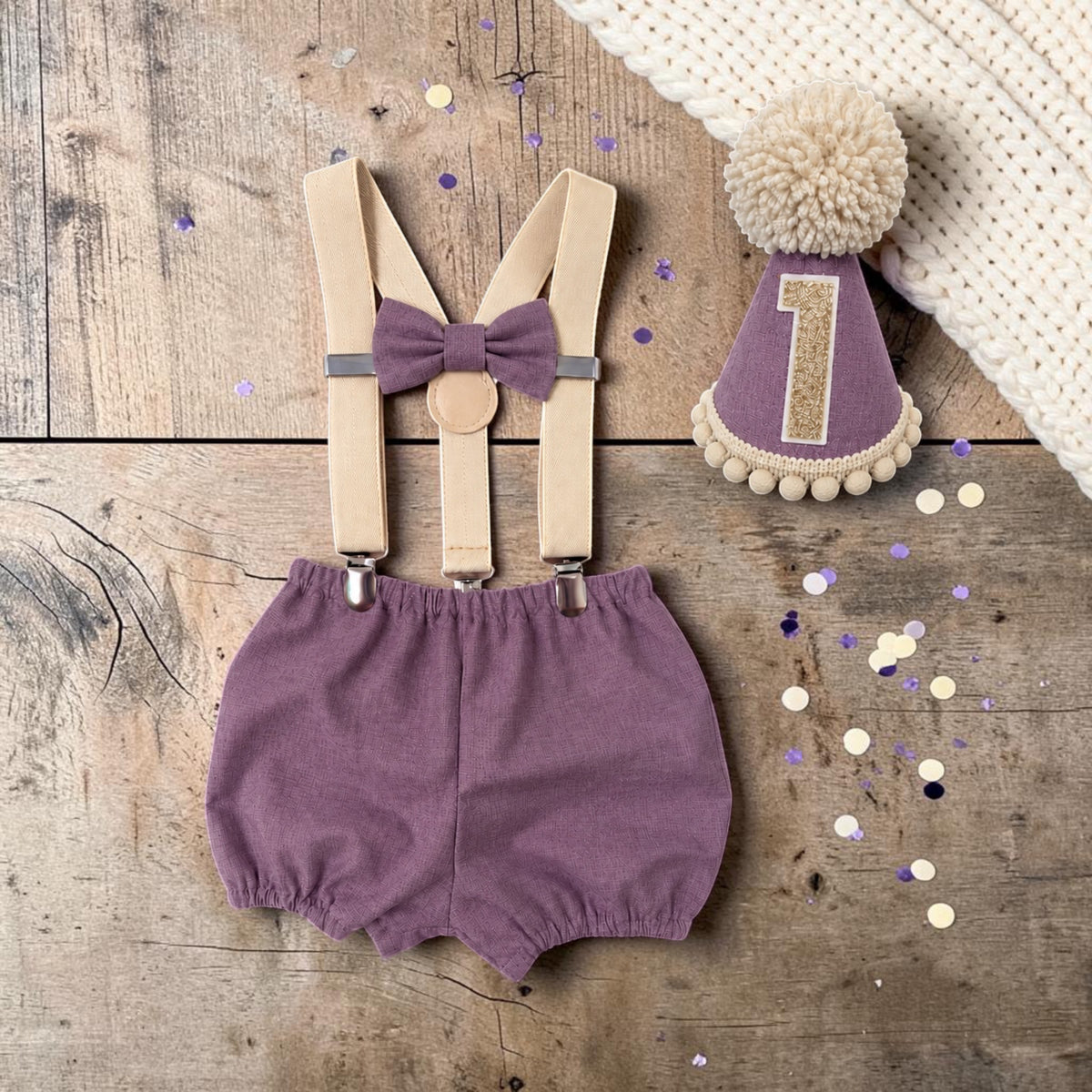 Handmade mauve birthday cake smash outfit with Moda Bella Solids cotton bloomer shorts, matching bow, beige braces and party hat with champagne glitter number one and fluffy stone-coloured pom-pom.