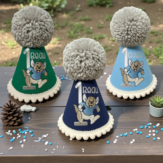Three party hats with pom-poms on a wooden surface with confetti.