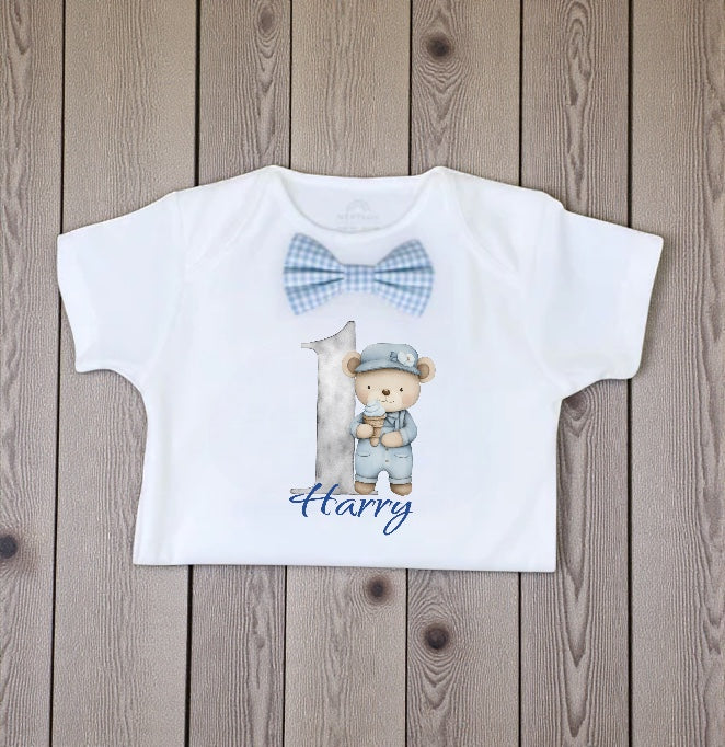 Personalised baby bodysuit with blue gingham bow tie and printed teddy bear first birthday design.