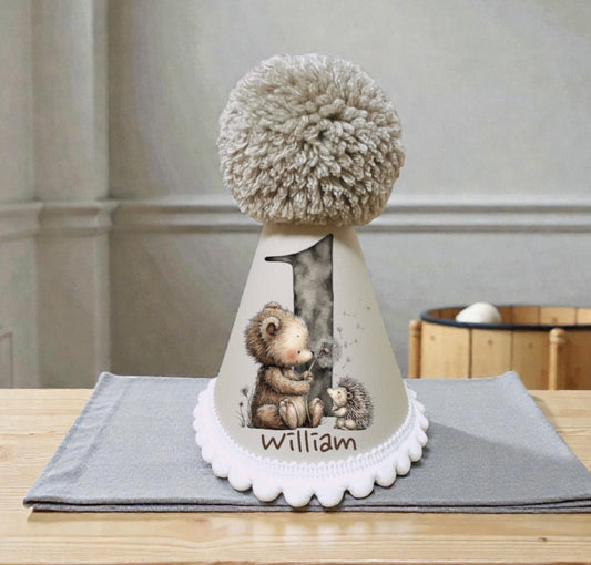 Personalised baby birthday hat with printed number one, woodland animals and child’s name
Handmade neutral birthday party hat with pom pom and white bobble trim