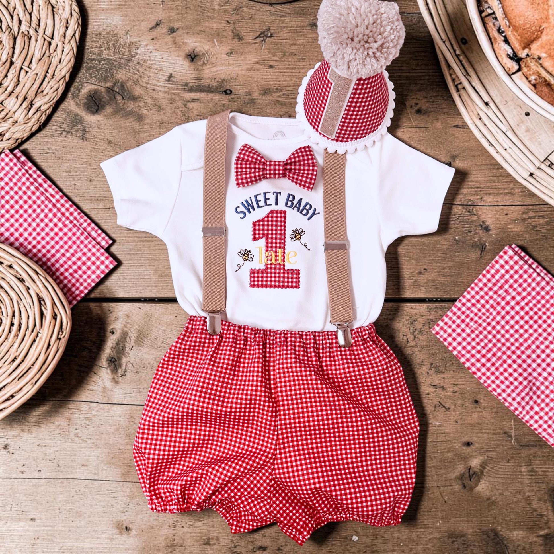 Handmade personalised red gingham first birthday outfit with embroidered bodysuit, suspenders and matching birthday hat for cake smash photos.