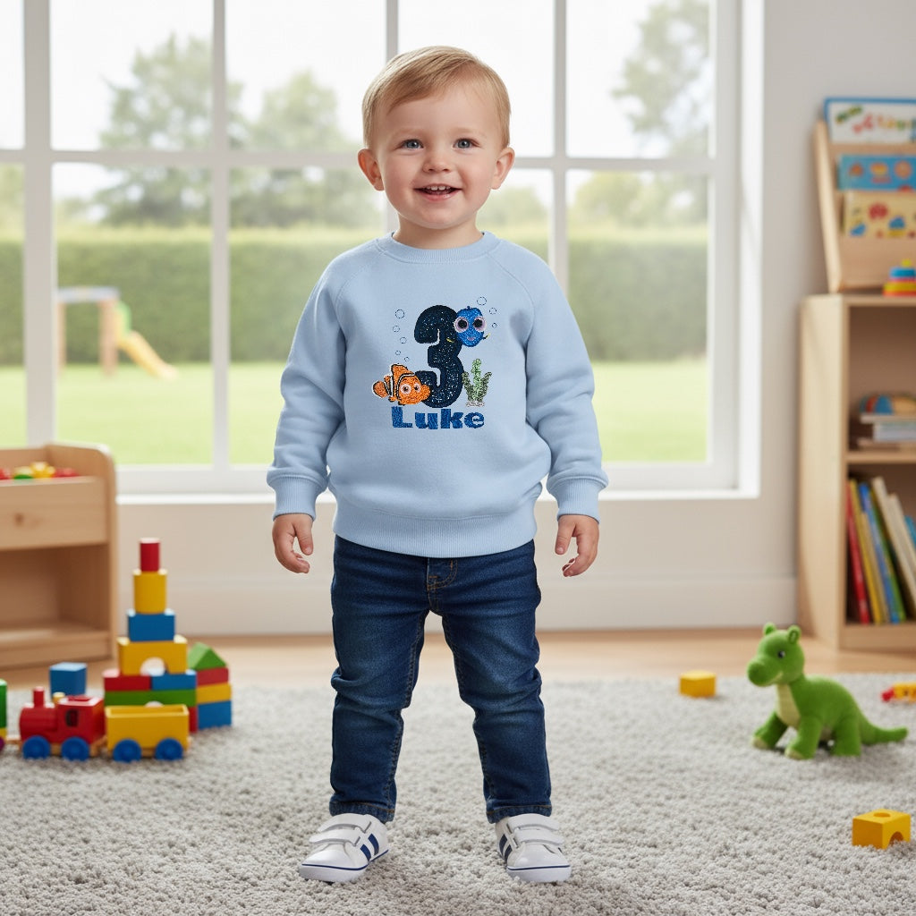 Light blue embroidered Nemo and Dory sweatshirt worn by smiling toddler