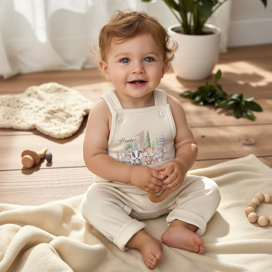 Smiling baby wearing personalised woodland romper with forest animal print and name detail